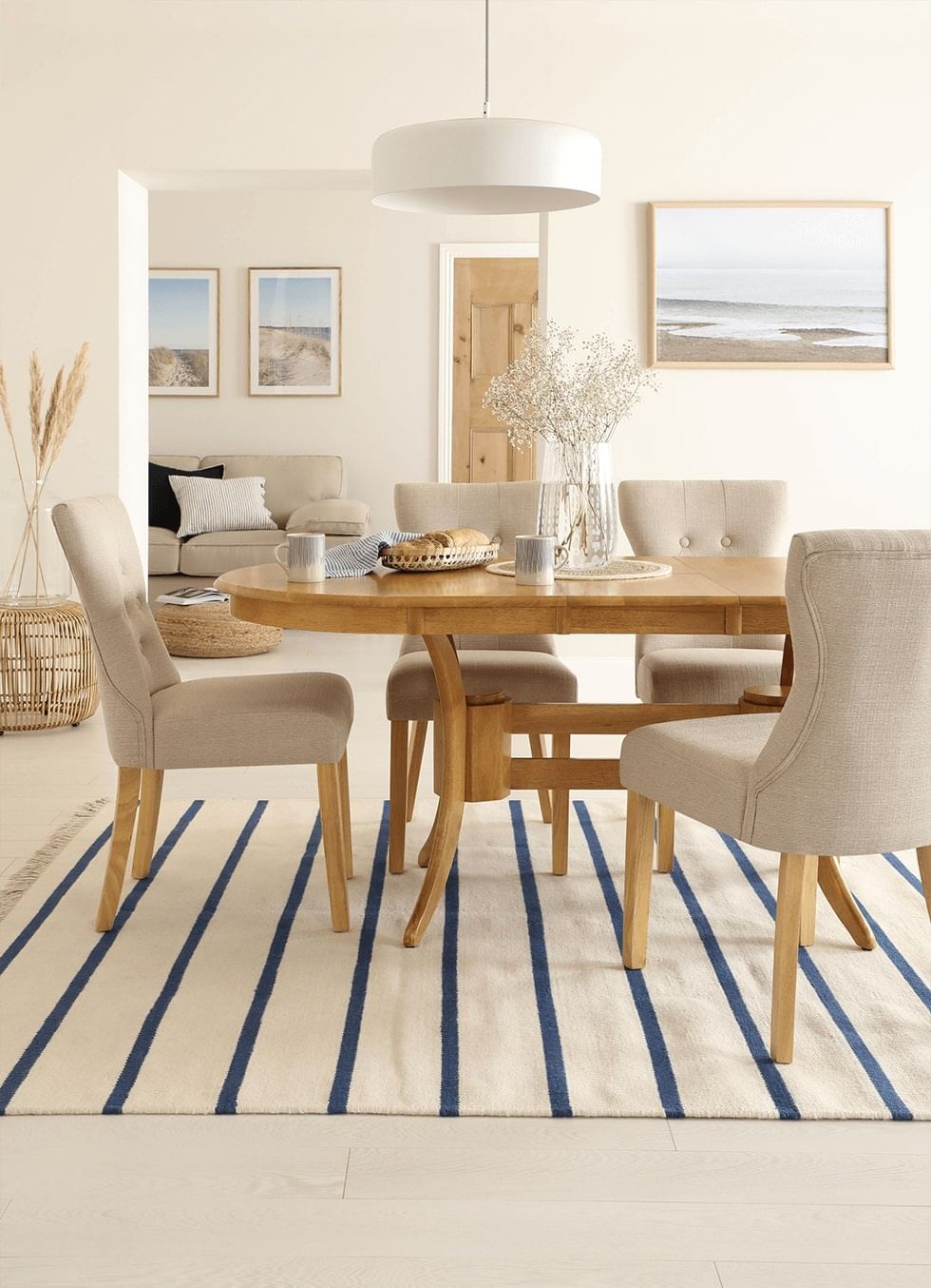 A striped rug under an oak dining table and beige fabric chairs