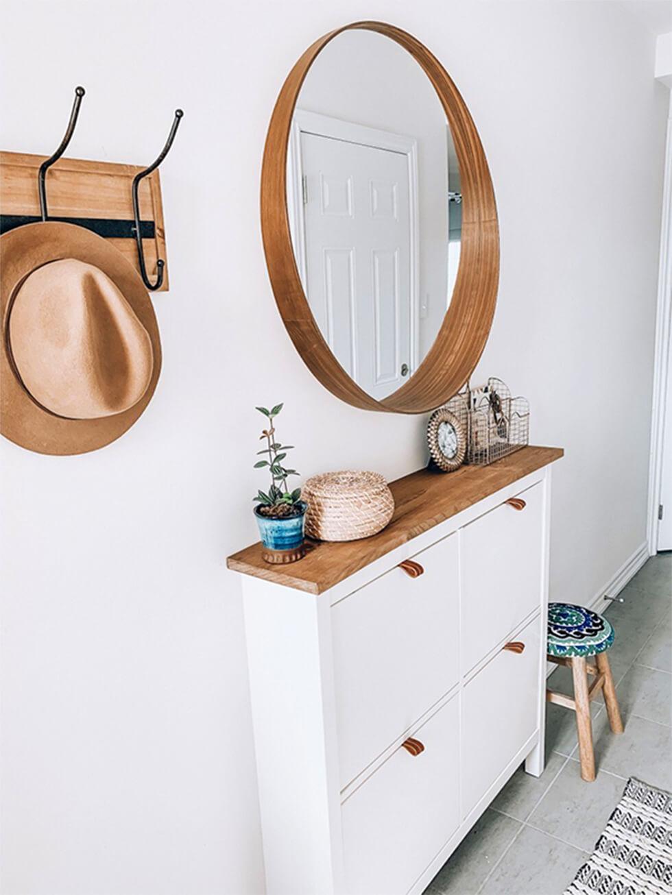 White hallway with storage closet and round mirror