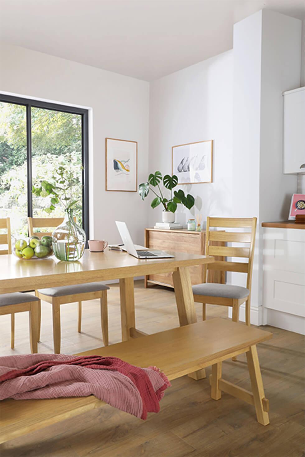 Working from home in an open plan kitchen with a wooden dining table and bench