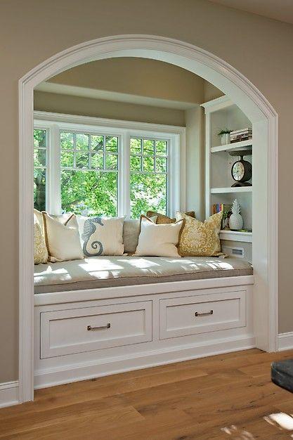 Window seat with pillows and bottom drawers.