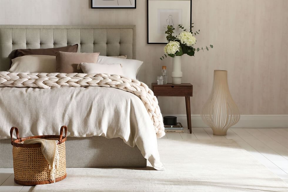 Elegant bedroom featuring a cosy bed and a chunky knit throw over it
