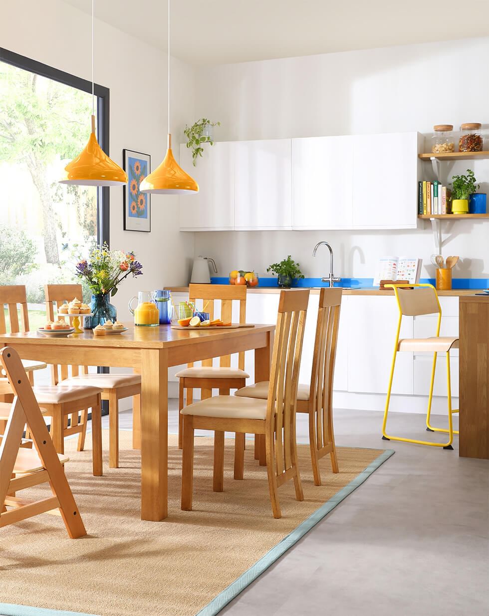 A bright dining room styled with Pantone 2023 London Fashion Week colours and a wooden dining set