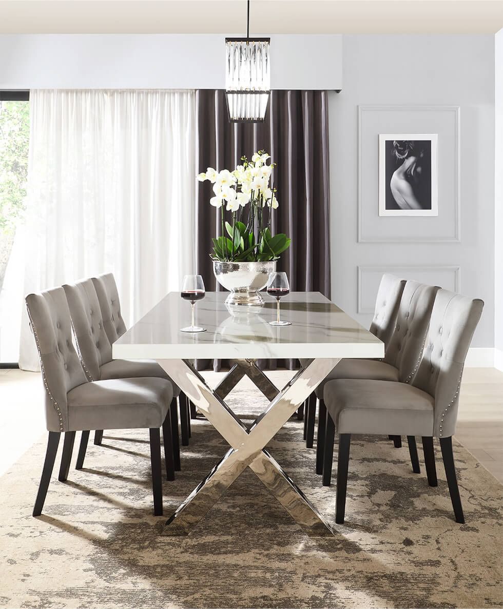 A contemporary dining room with a marble and chrome dining table, grey velvet chairs and light grey walls