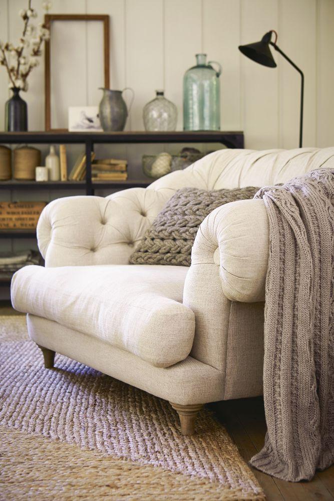 White sofa with knitted pillow and throw.