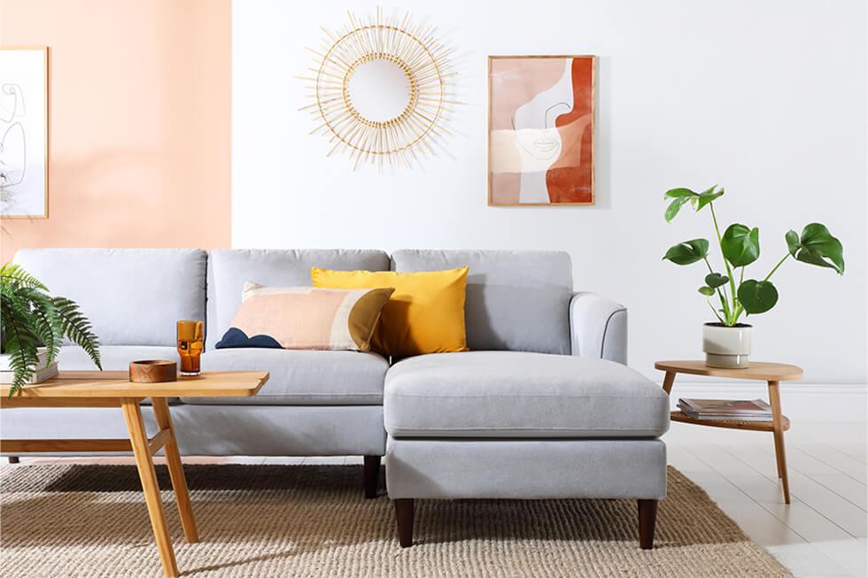 Colourful mid-century living room with grey fabric sofa, tables with tapered legs and sunburst decor