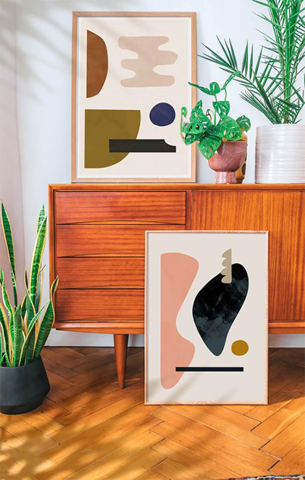 Framed mid-century art against a credenza with indoor plants