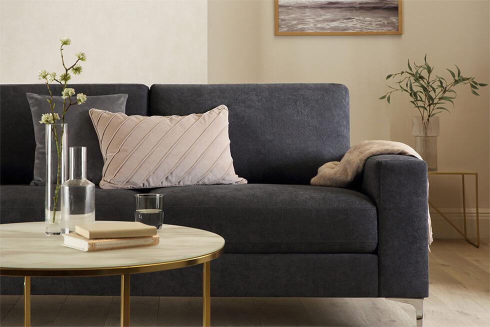 Neutral living room with dark grey fabric sofa with chrome legs and a round coffee table