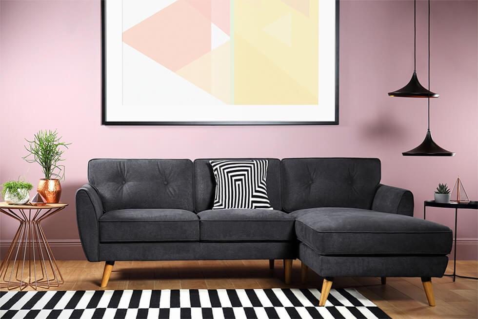 Statement pink living room with mid-century fabric sofa, monochrome rug and pendant lamps