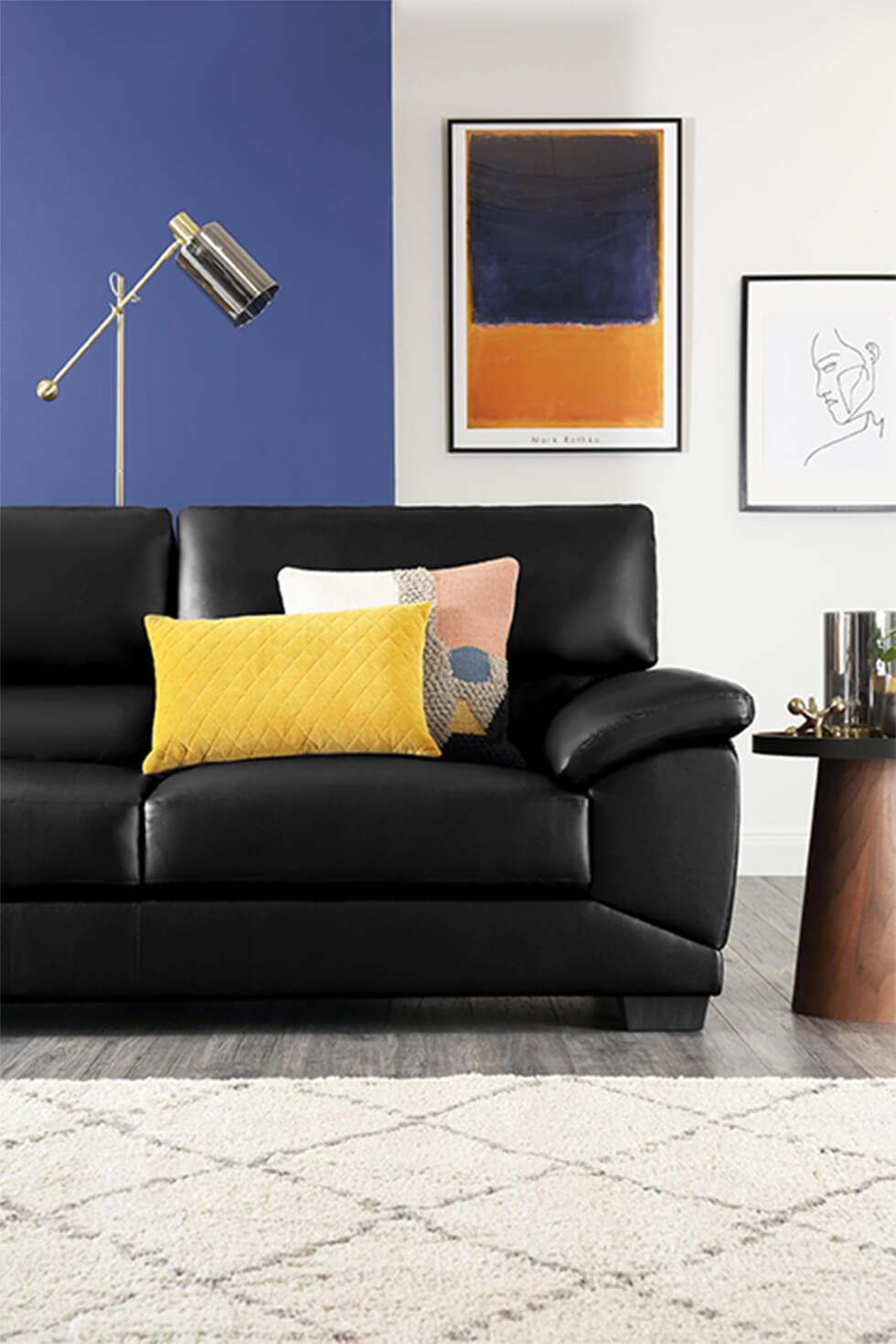 Black leather sofa with colourblock blue feature wall and framed art