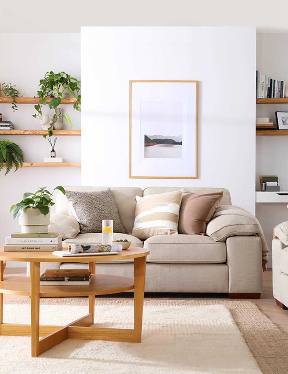 Light neutral living room with linen sofa and round wooden coffee table