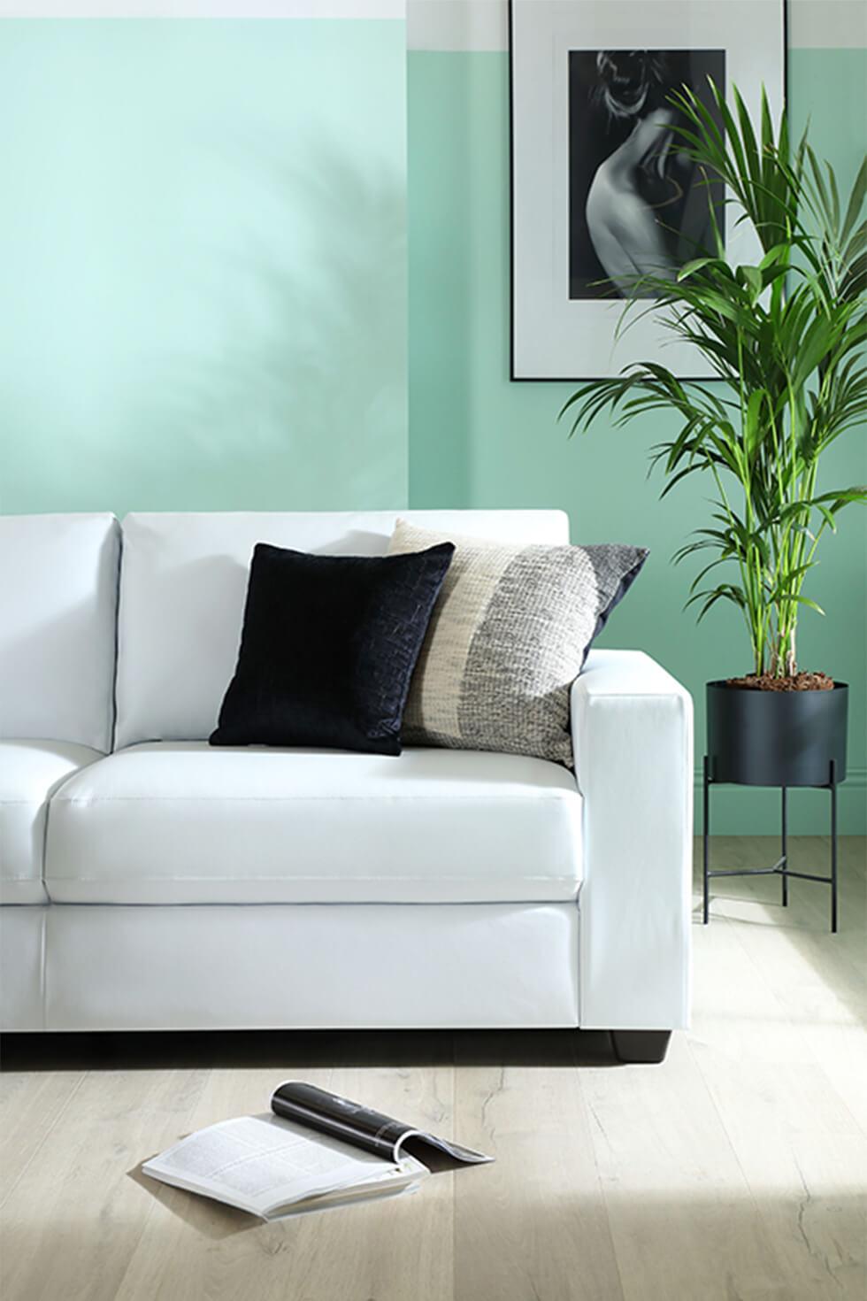 White leather sofa in a minimalist mint green tropical living room