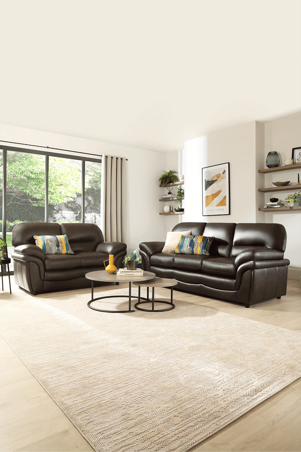 A brown leather sofa set in a neutral living room with wood flooring and yellow and green accessories