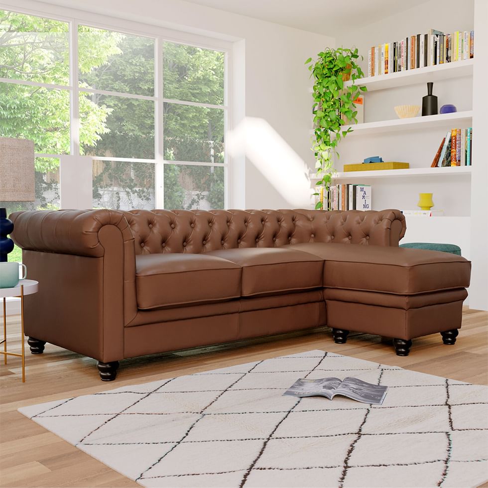 A tan leather Chesterfield L-Shape corner sofa with colourful books and accessories