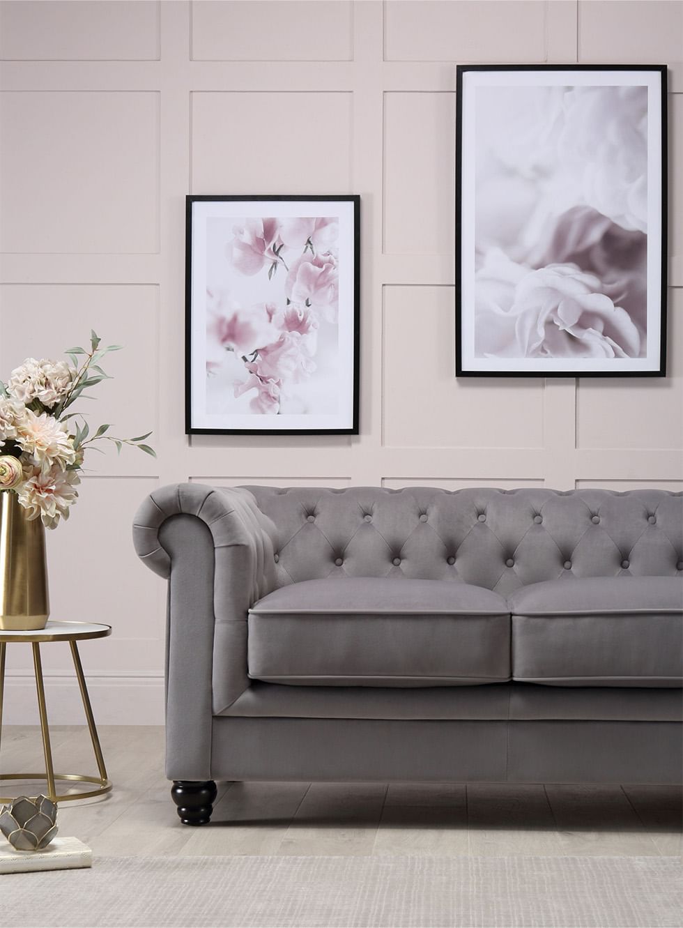 A grey velvet 2 seater Chesterfield sofa in a contemporary living room with pink wall panels