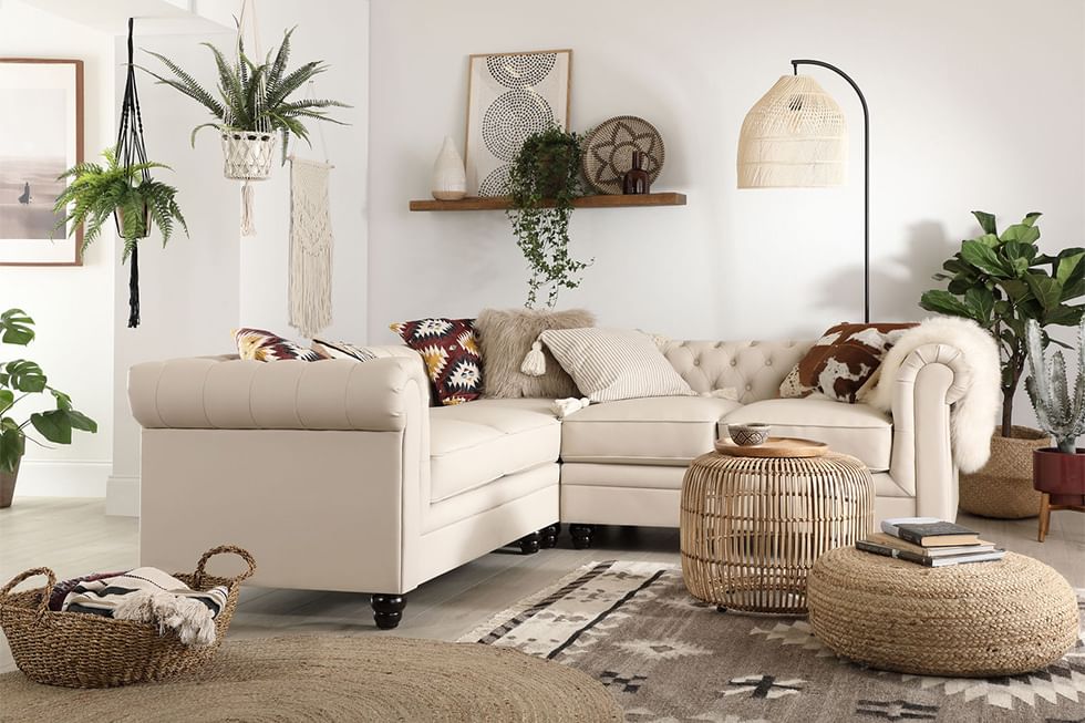 An ivory leather Chesterfield corner sofa in a neutral, modern bohemian styled living room