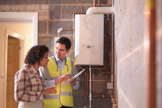 Woman consulting male technician next to the boiler.